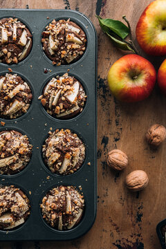 Vegan muffins topped with sliced apples and chopped walnuts