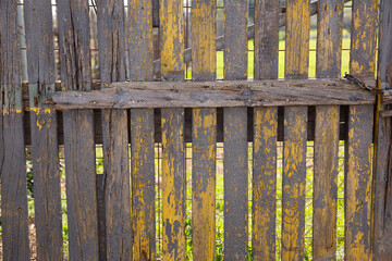 Closeup of rustic old wooden fence with rotten planks on sunny spring day..