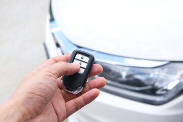 Man hand holding the car remote, he push the remote control to open the car door