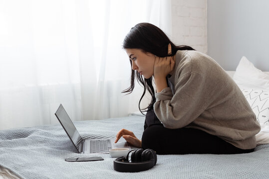 Young woman using laptop on bed