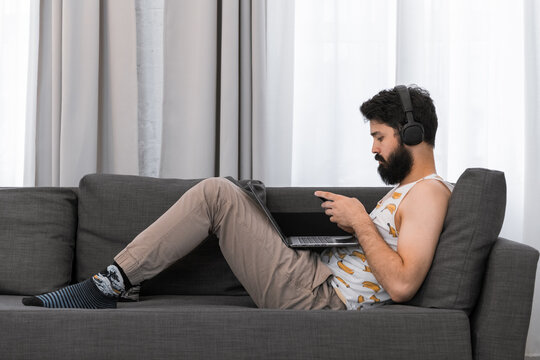 Male hipster using gadgets on sofa