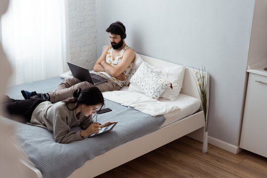 Couple using devices on bed in weekend