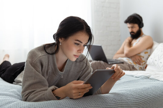 Young woman using tablet while resting near boyfriend