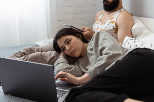 Young woman resting near boyfriend and using laptop