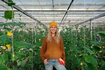Cheerful female farmer amidst cucumber plants