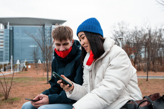 Happy diverse couple using smartphones in park