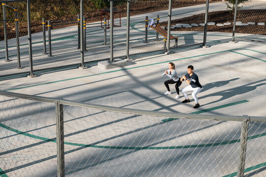 Young athletes squatting during workout on sports ground