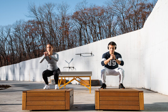 Sportsman and sportswoman jumping on boxes in autumn