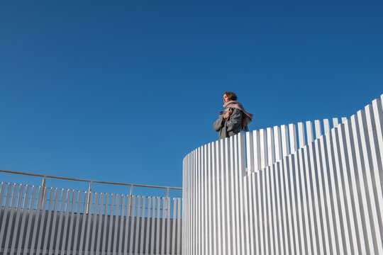Woman in outerwear resting on top of building