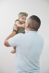 Padre latino compartiendo con su hija bebe, padre latino sonríe mientras carga a su bebé