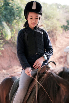 Asian little girl playing on horseback in the wild horse farm