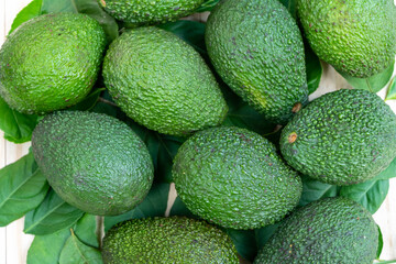 Avocado fruit with leaves on wooden background.