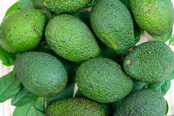 Avocado fruit with leaves on wooden background.