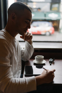 Man Drinking a Coffee and Working from a Coffee Shop