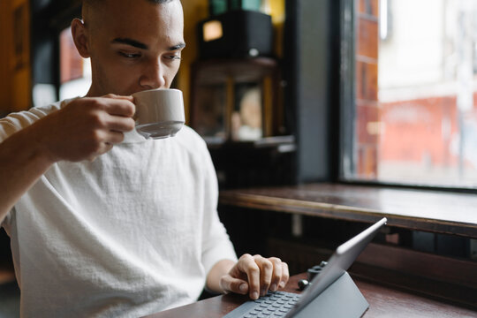 Man Drinking a Coffee and Working from a Coffee Shop