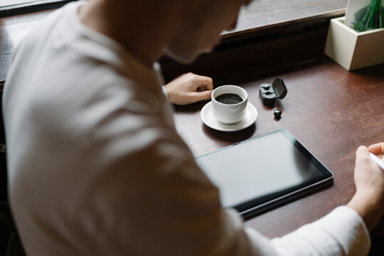 Man Drinking a Coffee and Working from a Coffee Shop