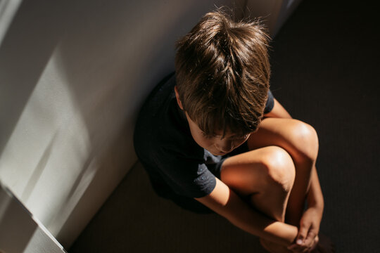 Young boy inside home and sad or upset