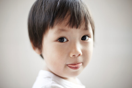 Close-up funny head portrait of cute Asian kid with clean background at home.