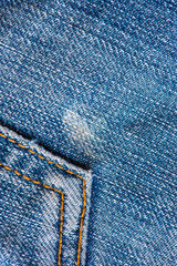 Detail of old blue jeans with yellow seams. Texture closeup background