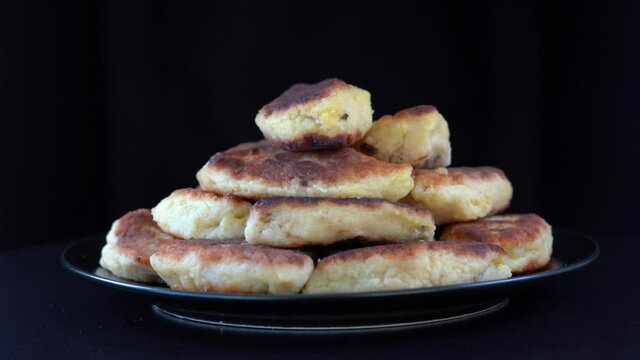 Potato cakes, ukrainian name potato zrazy, stuffed mushrooms or meat or cheese with herbs cream are fried in vegetable oil on black background, close up, rotates. Traditional Ukrainian cuisine