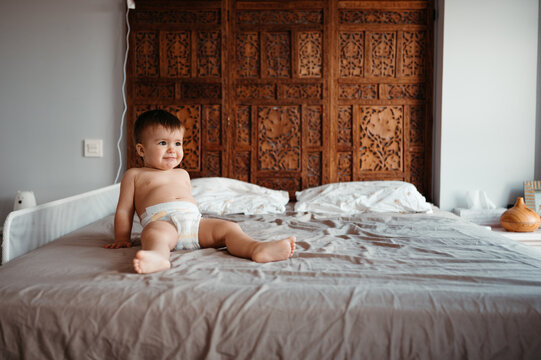 Funny baby resting on bed.