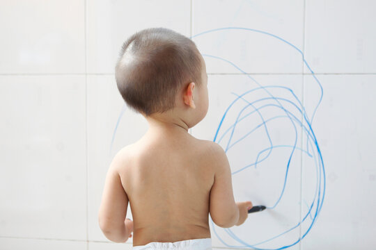Cute Asian kid painting casually on the wall at home
