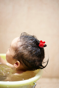 Cute Asian kid playing in the bath bucket in the bathroom
