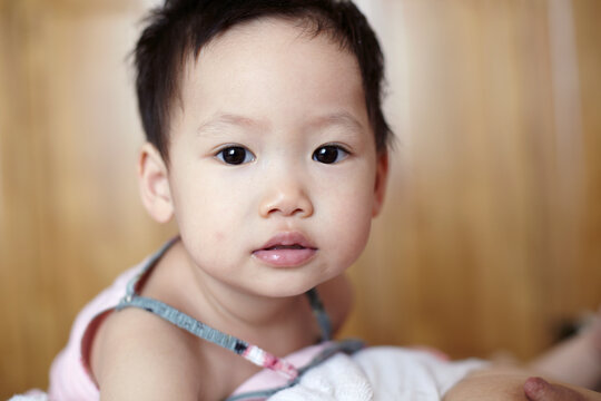 A close-up of a loving Asian child, lying on the bed, watching the camera. Just finished breast milk