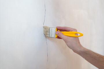 Construction man worker repairing a crack wall of a home, plastering cement on wall. Builder...