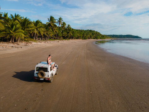 Aerial shot of a car in an empty caribbean beach.