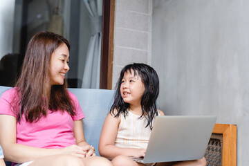 Happy asian mother and kid girl with laptop computer at home.teacher mother is teach her children during coronavirus covid19 lockdown.Education, Online learning, back to school.School kid.Homeschool.