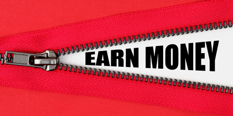 Against the background of red fabric, a zipper opens, on the white surface the inscription - EARN...