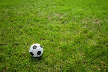 Football soccer ball on green grass field with big copy space