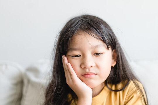 Asian kid girl toothache.kid suffering from toothache.TMD and TMJ healthcare Joint and Muscle Disorder.Asian child hand on cheek face as suffering from facial pain, mumps toothache.Dental health care.