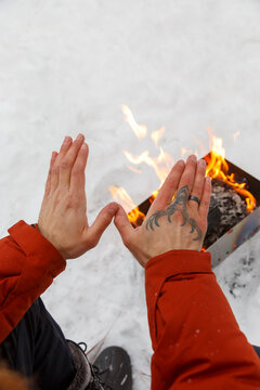 Crop person warming hands over brazier in winter