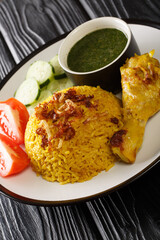 Thai Chicken Biryani kao mok gai served with Dipping Sauce and fresh vegetables closeup in the plate. Vertical