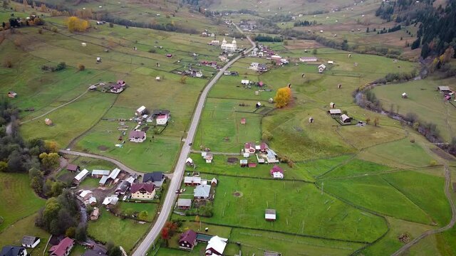Scenic aerial panoramic view of idyllic rolling hills spring landscape in the Alps with lush green mountain pastures and alpine mountain tops in the background in evening light at sunset