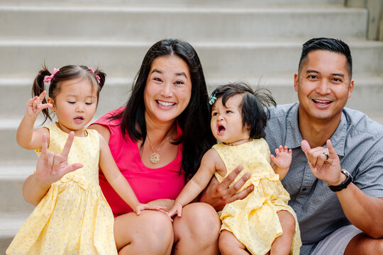 Young Asian Family On Steps Practices Sign Language
