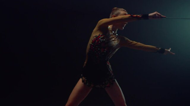 Girl gymnast dancing with ribbon indoors. Athlete doing rhythmic gymnastics.