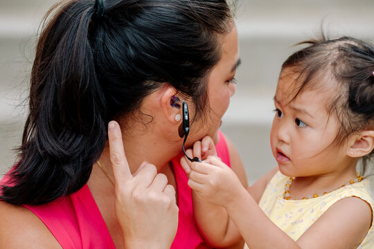 Deaf Asian mother teaches serious young daughter about cochlear implant