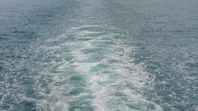 Water trail foaming behind ferry boat. Ship wake in sea. View behind car ferry