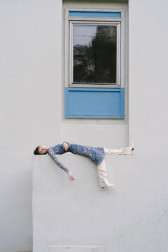 Stylish woman lying on fence of building
