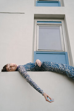 a woman in a stylish dress lies on the parapet of a building