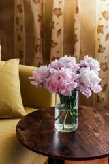 Beauty bouquet of pink peonies on a wooden table in a cozy room. Home still life interior concept