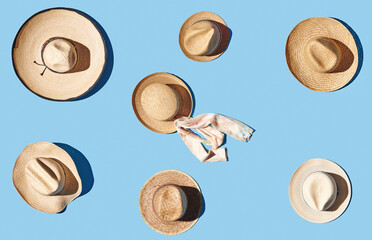 Straw hat with ribbon on blue pastel background, top view