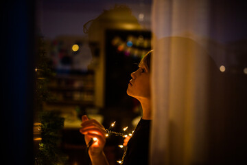 View of young boy holding string of lights for Christmas tree inside home