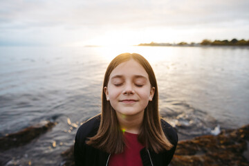 Young girl on beach with eyes closed in expectation