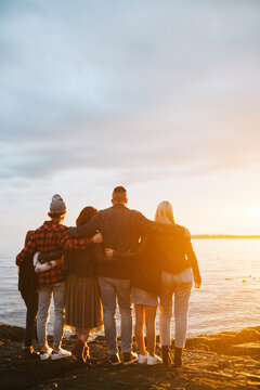 Family staring into the sunset together on rocky beach. 