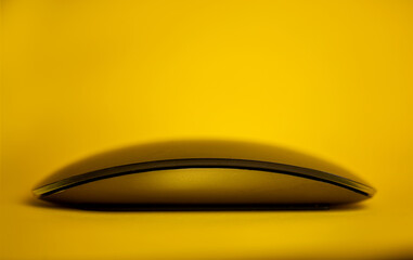 Modern tech wireless computer mouse on a yellow background.