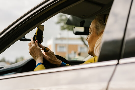 senior woman placing her phone on the gps holder at car 
